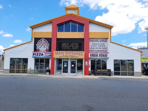 A colorful building with signs for pizza, tobacco, and various shops, featuring a prominent main entrance.