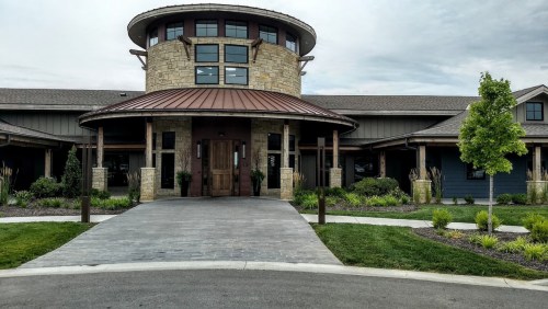 Modern building with a circular entrance, stone accents, and landscaped surroundings.