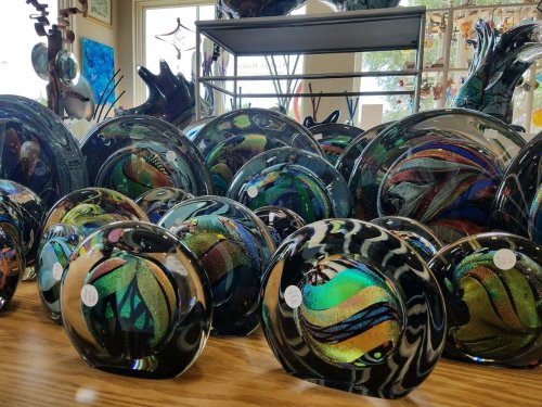A collection of colorful glass art pieces displayed on a table, featuring swirling patterns and vibrant hues.