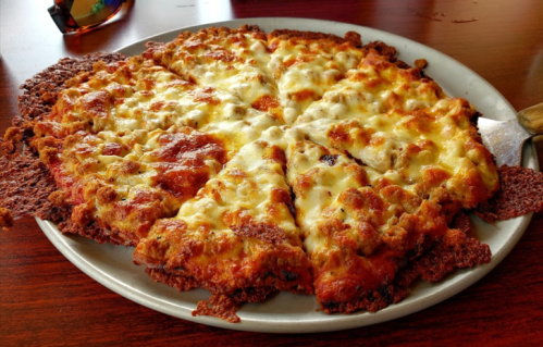 A round pizza with a crispy crust, topped with melted cheese and tomato sauce, sliced into eight pieces on a plate.