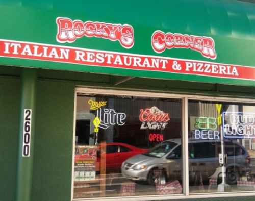 Sign for Rocky's Corner Italian Restaurant & Pizzeria, featuring neon "Open" and beer advertisements in the window.