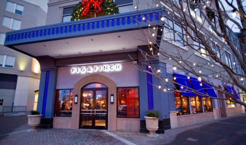 Exterior of Pig & Finch restaurant, decorated for the holidays with a wreath and string lights.