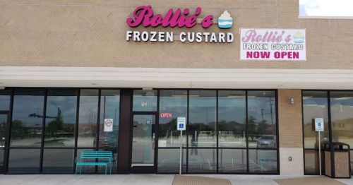 Exterior of Rollie's Frozen Custard shop, featuring a large sign that says "NOW OPEN" and glass windows.
