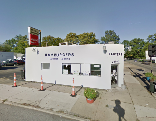 A small white building with a sign reading "Carter's Hamburgers" and a fountain service, located on a street corner.