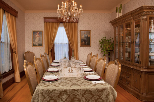 Elegant dining room with a long table set for a meal, adorned with a chandelier and vintage decor.