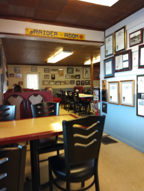 Interior of a diner with red booths, wooden tables, and walls adorned with framed photos and certificates.
