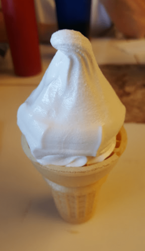 A soft-serve ice cream cone with a smooth, white swirl on top, sitting in a waffle cone.