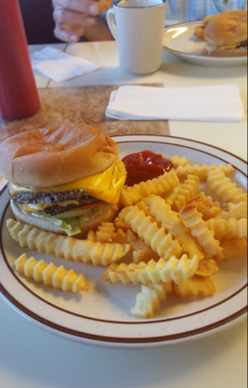 A cheeseburger with lettuce on a plate, accompanied by crinkle-cut fries and a side of ketchup.