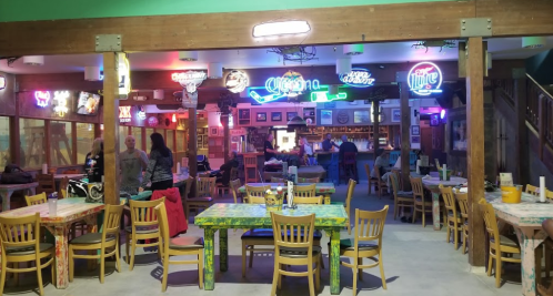 A vibrant restaurant interior with colorful tables, neon signs, and patrons enjoying their meals.