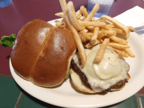 A cheeseburger with melted cheese on a bun, served with a side of crispy French fries.