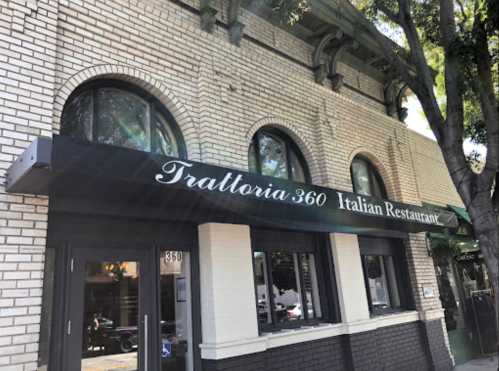 Exterior of Trattoria 360, an Italian restaurant, featuring a black awning and large windows.