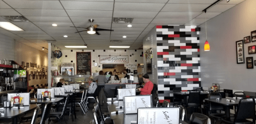 A cozy diner interior with black and white decor, tables set for dining, and a counter in the background.