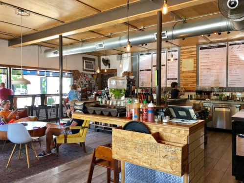 A cozy café interior with wooden accents, a bar area, and patrons enjoying their time at tables.
