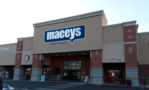 Exterior of a Macey's grocery store with a "happy shopping" sign and a Starbucks on the side.