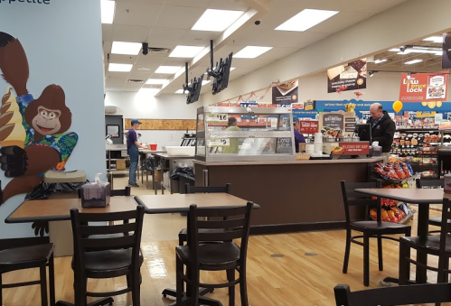 A casual dining area with tables, a service counter, and a colorful mural featuring a gorilla. Staff are visible in the background.