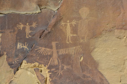 Petroglyphs on rock surface depicting human figures and a bird, showcasing ancient artistic expressions.