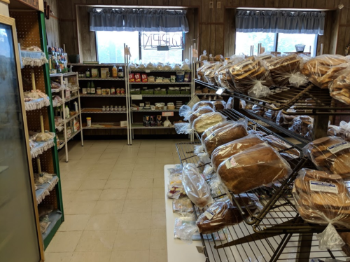 Interior of a bakery with shelves of bread and various packaged goods on display.