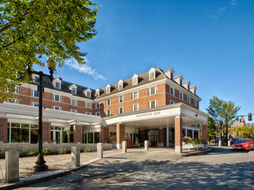 Exterior view of Hanover Inn, featuring a brick facade and a clear blue sky. Trees line the street in front.