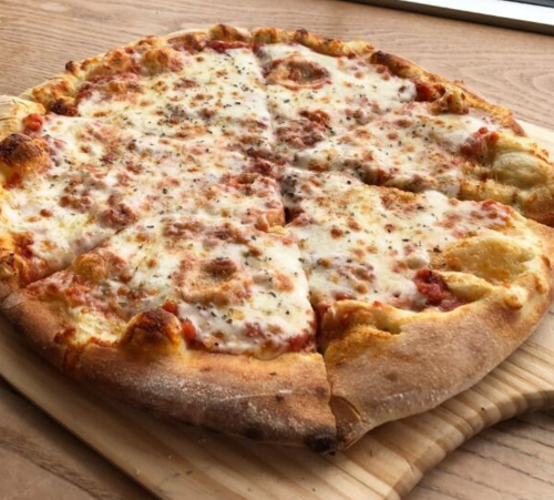 A freshly baked cheese pizza with a golden crust, sliced into eight pieces, resting on a wooden board.