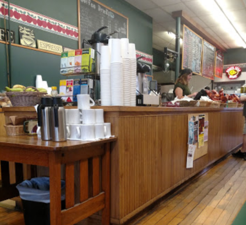 A cozy café interior with a wooden counter, coffee equipment, and a barista serving customers.