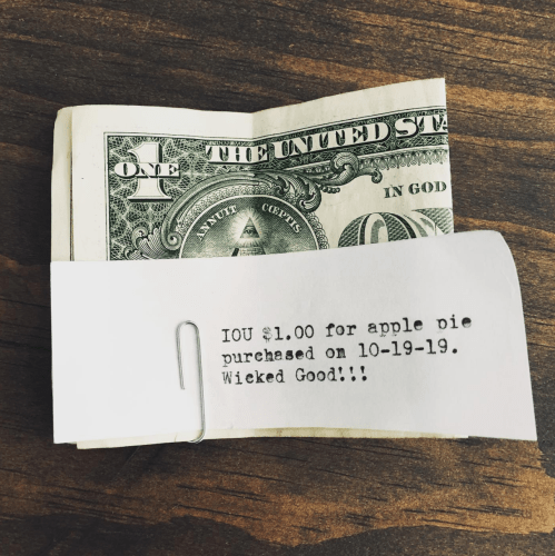 A one-dollar bill with a note attached, stating an IOU for an apple pie purchased on 10-19-19.