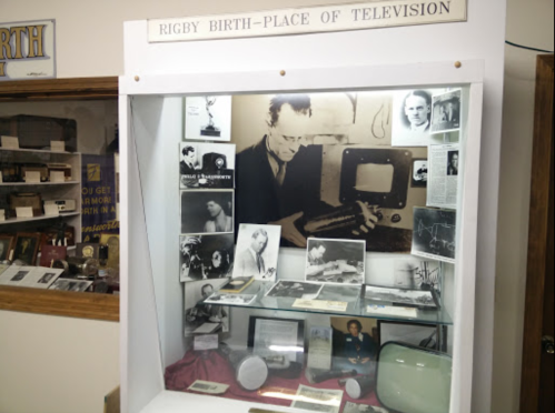 Display case featuring historical photos and artifacts related to the birthplace of television in Rigby.