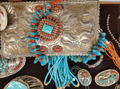 A collection of silver jewelry featuring turquoise and coral stones, displayed on a textured surface.
