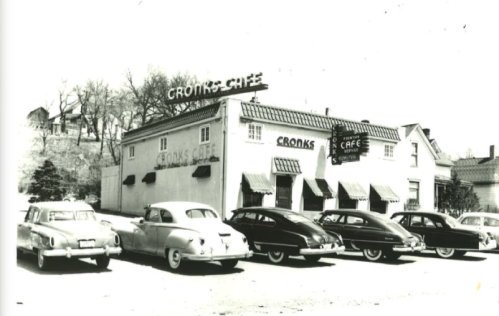 Black and white photo of Crooks Café with vintage cars parked outside, showcasing mid-20th century architecture.