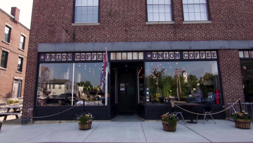 Exterior of Union Coffee shop with large windows, brick facade, and potted plants on the sidewalk.