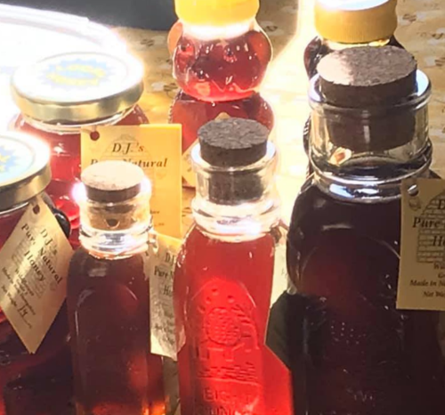 Bottles of amber-colored syrup with cork stoppers and labels, arranged on a table with soft lighting.