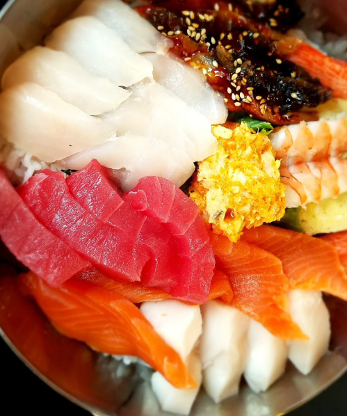 A colorful assortment of sushi and sashimi, including various fish and garnishes, served in a bowl.