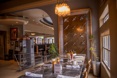 A stylish restaurant interior featuring a marble table, decorative wall, and cozy seating area.