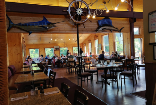 A cozy restaurant interior with wooden decor, tables set for dining, and patrons enjoying their meals.