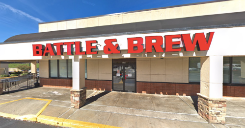 Exterior of a building with a large red sign that reads "BATTLE & BREW," featuring a modern design and clear blue sky.