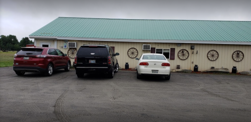 Three cars parked in front of a building with a green roof and decorative wheel accents on the walls.
