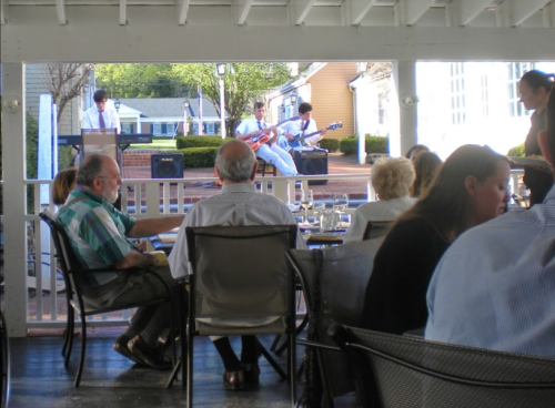 A live band performs outdoors while diners enjoy their meals at a restaurant.