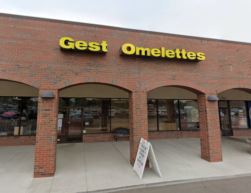 Exterior of a brick building with a sign reading "Gest Omelettes" and an open sign in the window.