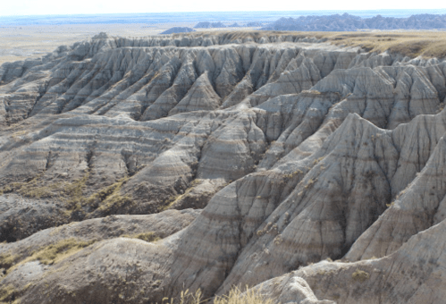 A rugged landscape of layered, jagged rock formations under a clear blue sky.