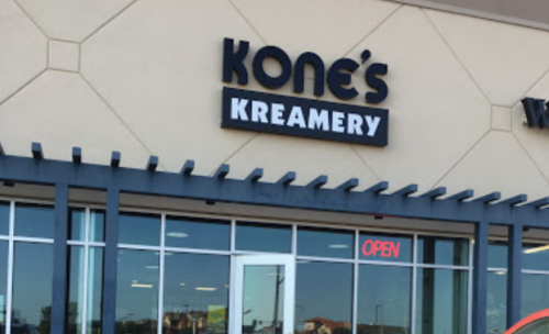 Sign for Kone's Kreamery with an "Open" indicator on the door, set against a light-colored building exterior.