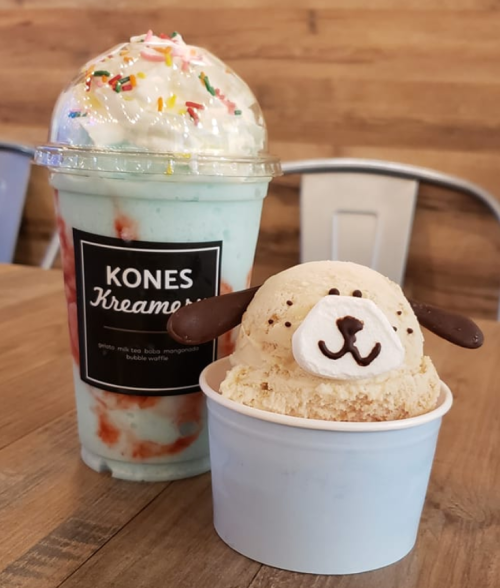 A colorful milkshake topped with whipped cream and sprinkles next to a dog-shaped ice cream in a cup.