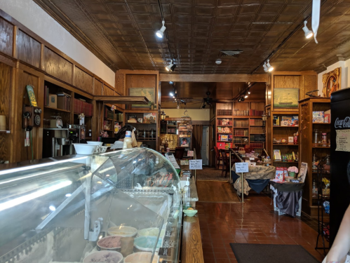A cozy ice cream shop interior with wooden shelves, a display case of ice cream, and a warm, inviting atmosphere.