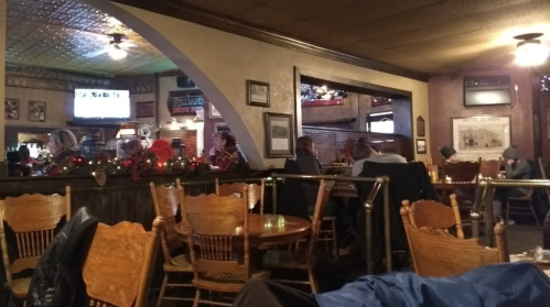 A cozy restaurant interior with wooden tables, chairs, and festive decorations, featuring patrons enjoying their meals.
