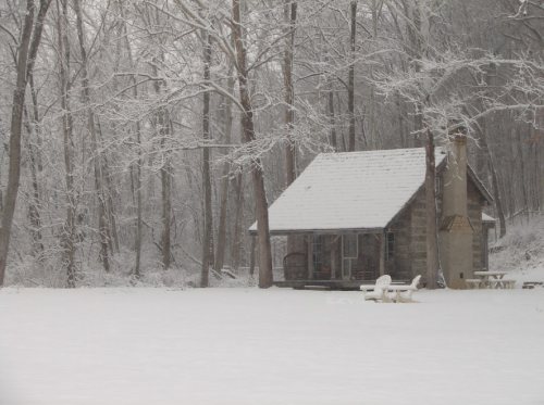 A cozy cabin surrounded by snow-covered trees in a winter landscape.