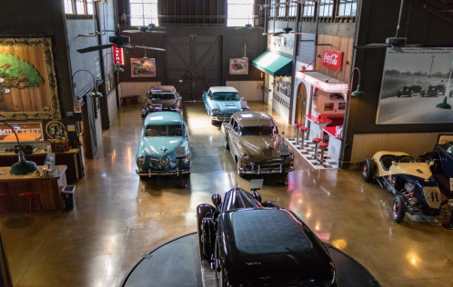 A vintage car museum featuring classic cars, retro decor, and a diner-style area with a Coca-Cola sign.