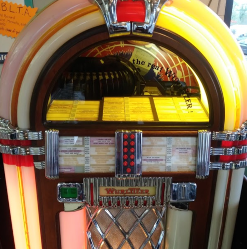 A vintage jukebox with colorful lights and a wooden finish, displaying song titles and a classic design.