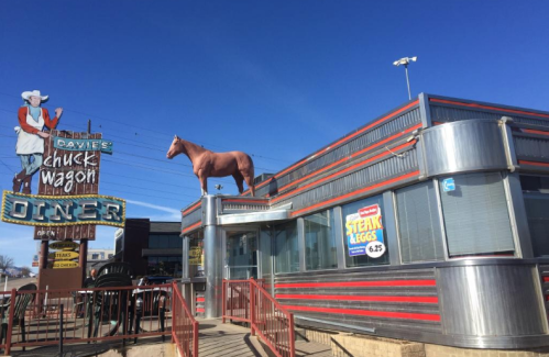 A retro diner with a horse statue on the roof and a vintage sign reading "Davies Chuck Wagon Diner."