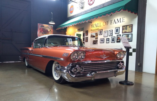 A vintage 1958 Chevrolet car displayed in a museum, featuring a shiny copper exterior and classic chrome details.