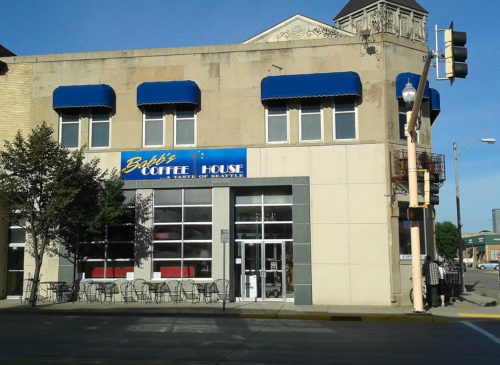 Exterior of Bob's Coffee House, featuring blue awnings and outdoor seating, located in a city setting.
