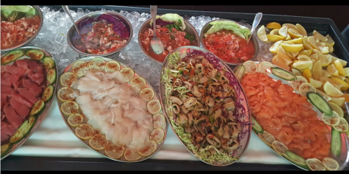 A seafood platter featuring various fish, salads, and lemon wedges, arranged on ice in decorative bowls.