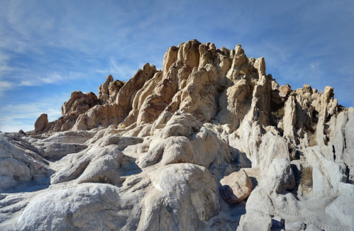 Rocky terrain with rugged formations under a blue sky, showcasing natural textures and shadows.